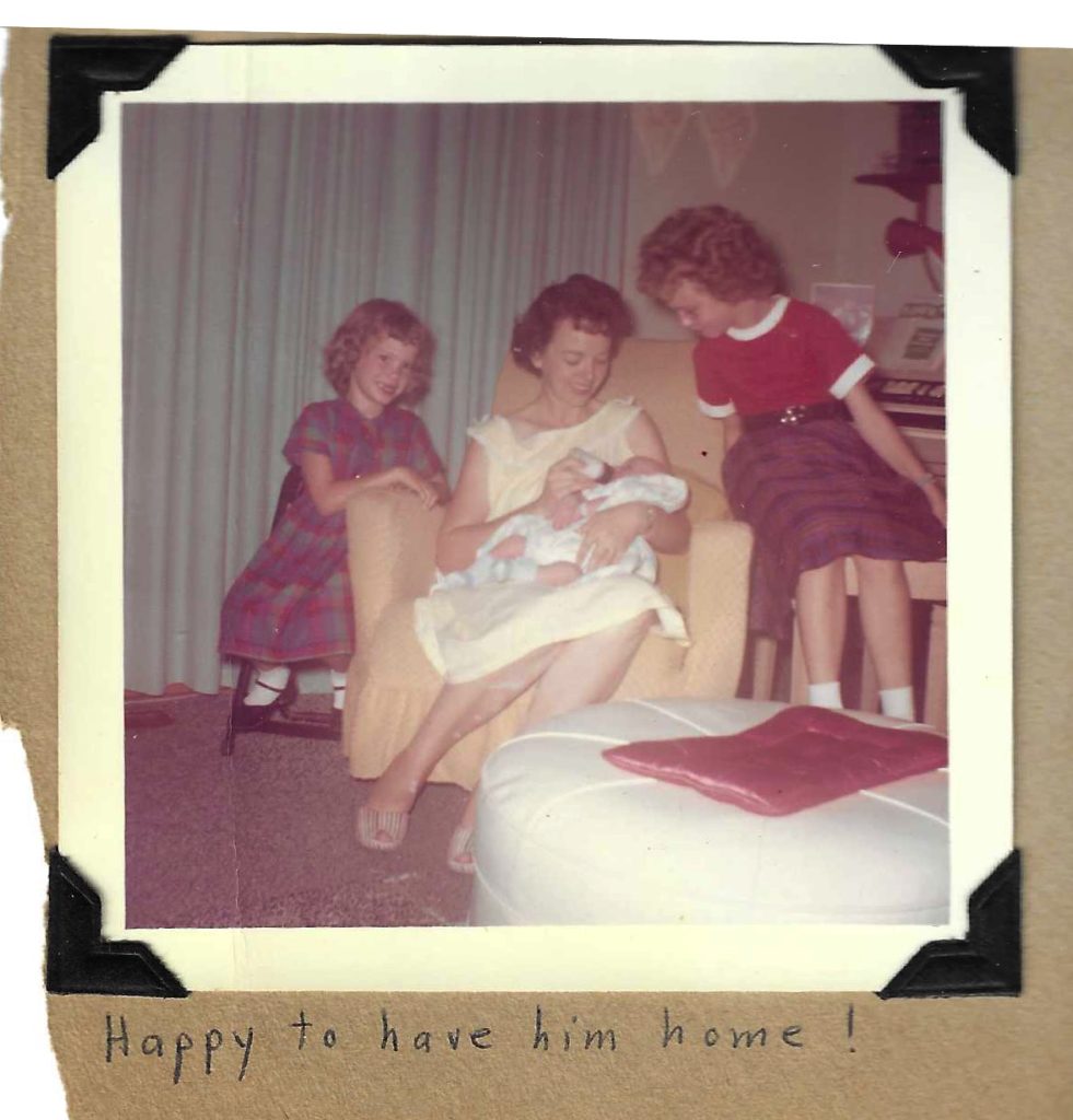 Terrill as a newborn babe, with Mom and sisters, with handwritten text 'Happy to have him home!'