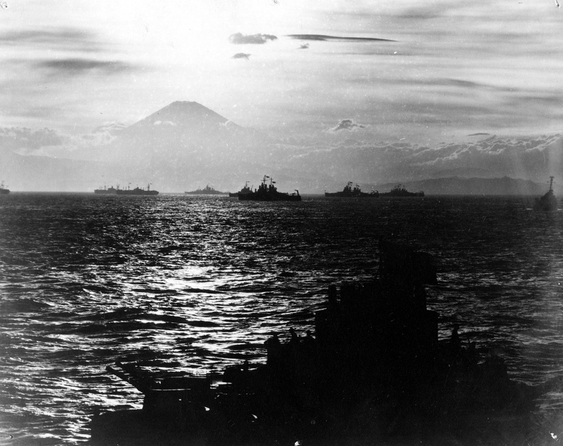 Black and white photo of ships in Tokyo Bay, a volcano in the background