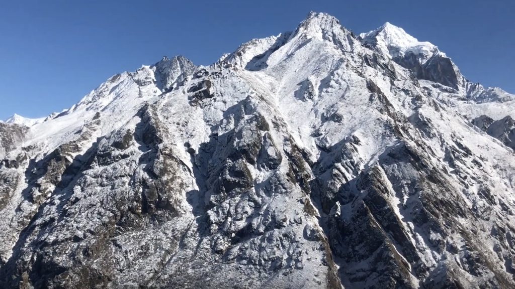 view out the helicopter window of a massive snowy mountain