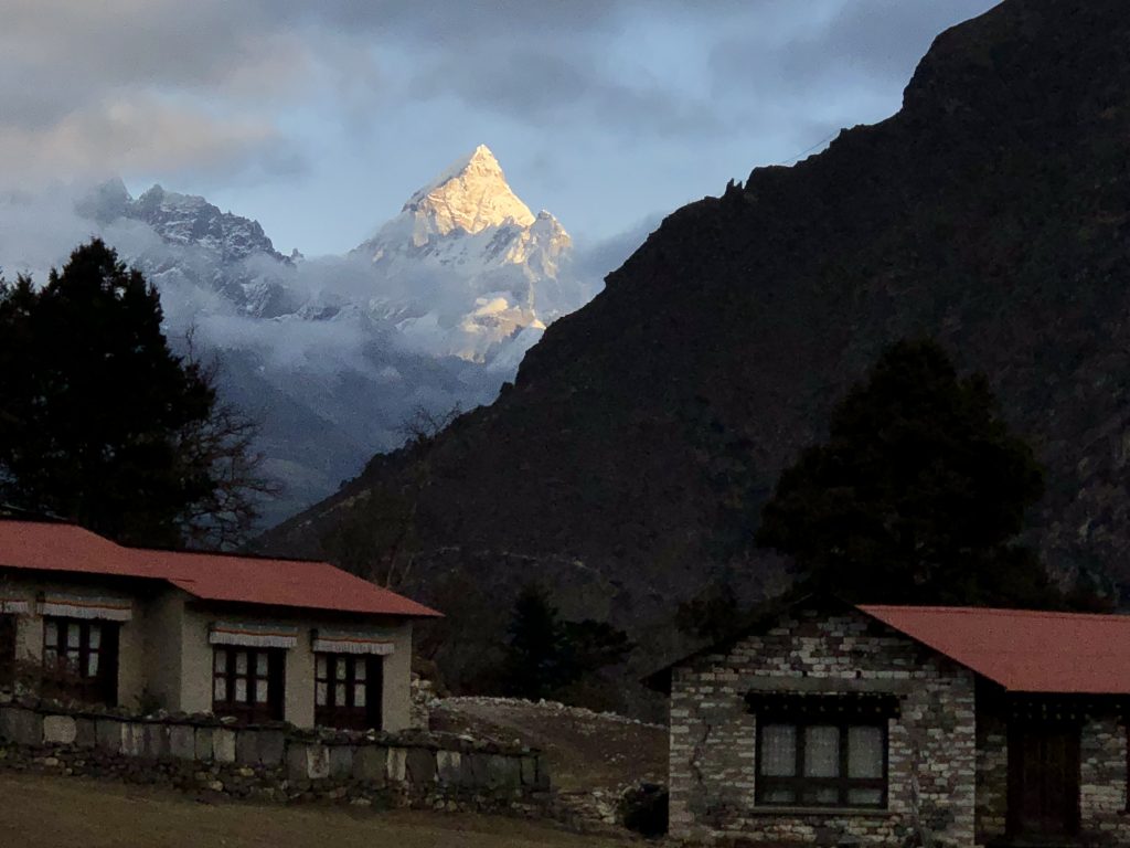 A sharp snowy peak gleams in the first sunlight over a Buddhist monastery