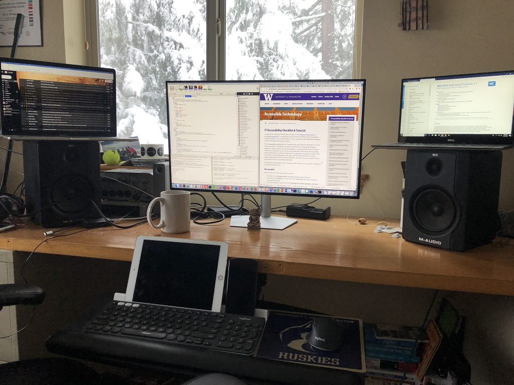 Terrill's home office, one large monitor flanked by laptops